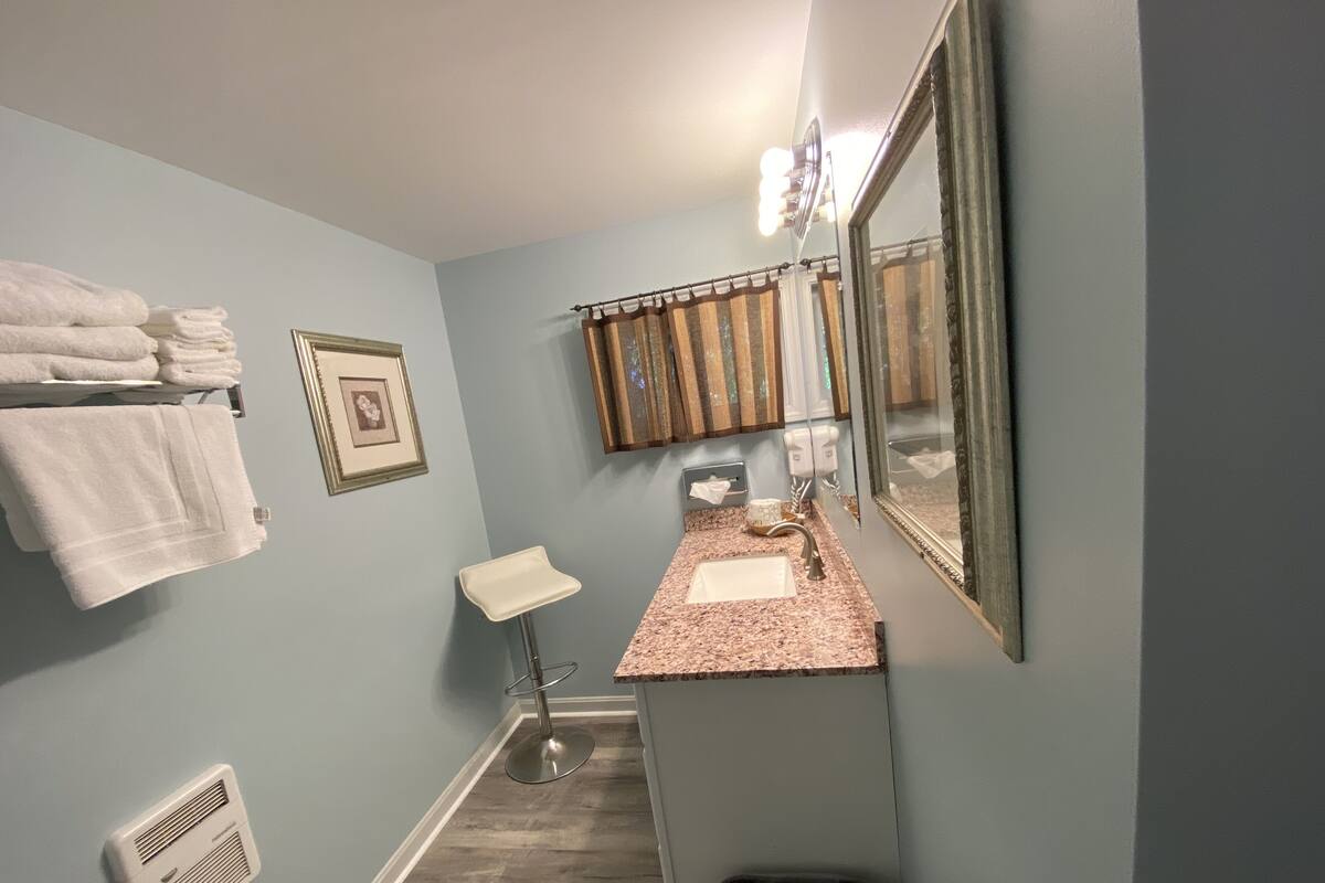 A bathroom with a sink, mirror, towel rack, and a trash bin.