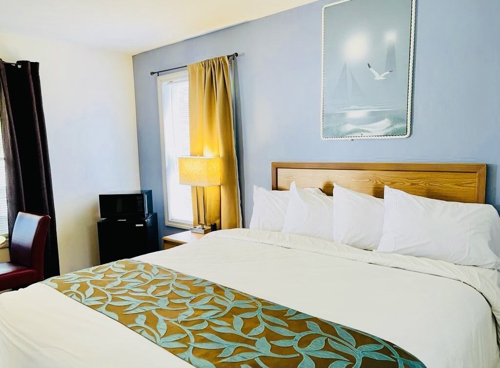A hotel room with a bed, a TV, a desk, and a chair.