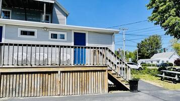 A two-story building with a wooden deck and a blue door.