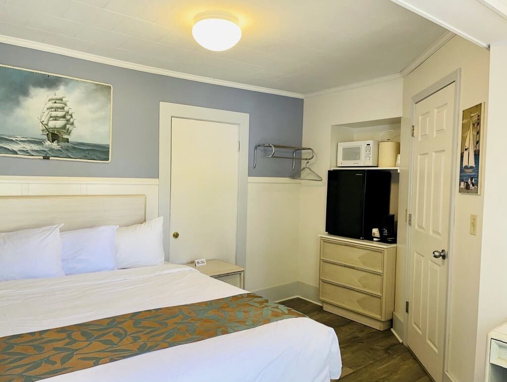 A hotel room with a bed, a microwave, a TV, and a door.