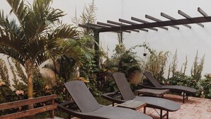 A patio area with wooden benches and two lounge chairs. - Casa Rosario (Valladolid)