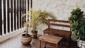 A room with a stone wall, a wooden bench, a small table, and potted plants. - Casa Rosario (Valladolid)