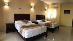 A hotel room with two beds, each with a wooden headboard, white bedding, and a brown throw blanket. There are wall-mounted lights and an air conditioning unit on the wall. - Casa Rosario (Valladolid)