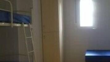 A room with a bunk bed, a wardrobe, and a small window.
