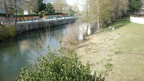 A river with a bridge, trees, and buildings in the background. - Pensión Albergue Puente Ribeira - Hostel (Sarria)