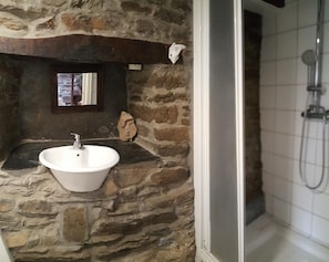 A stone bathroom with a sink and shower. - Pensión Albergue A Pedra (Sarria)