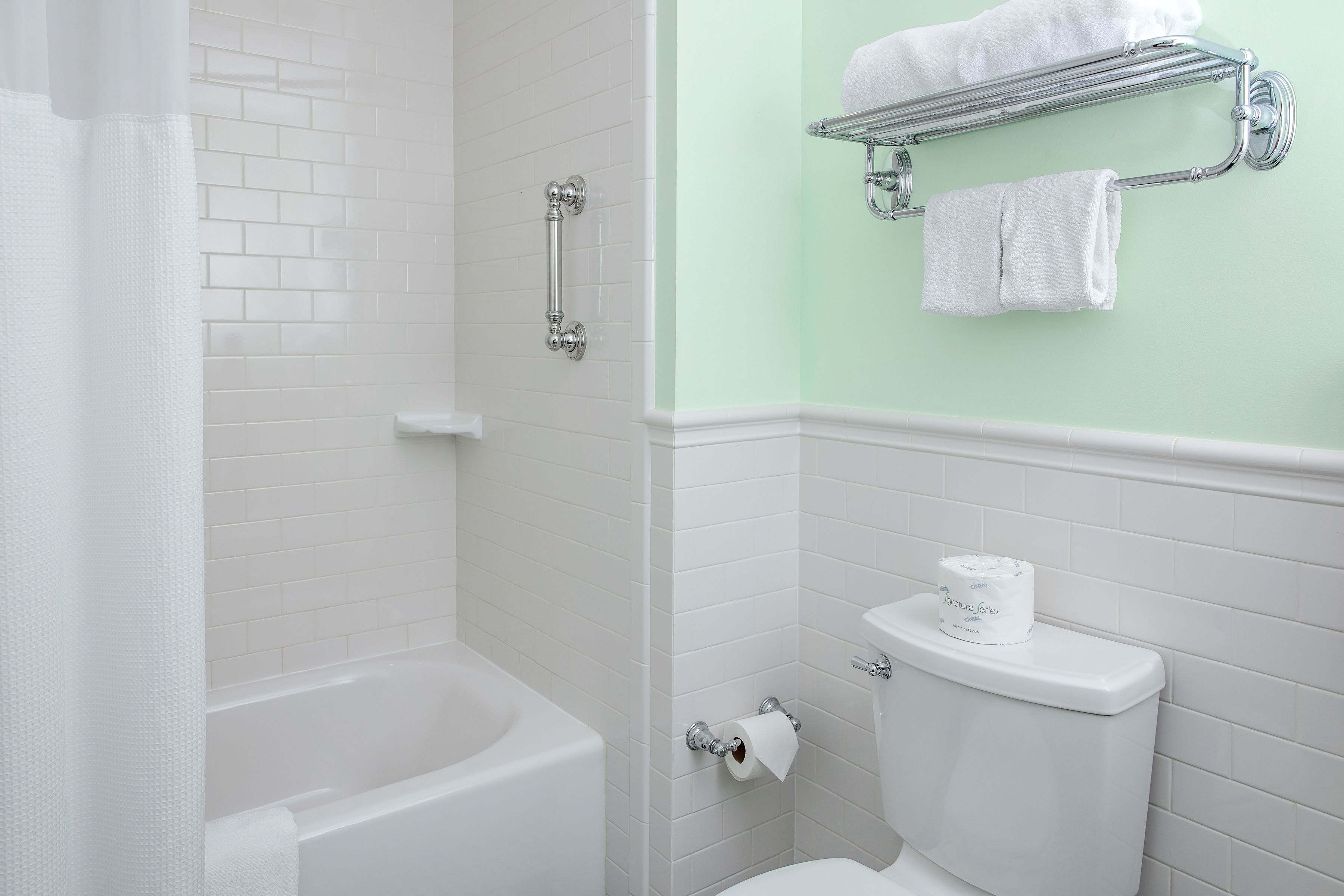 A bathroom with a white bathtub, a toilet, and a shower area.