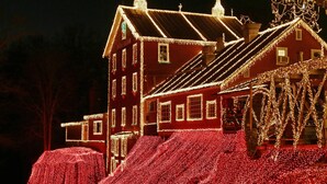 A large, red building with multiple windows and a sloped roof, adorned with numerous lights.