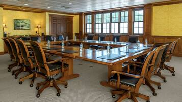 A conference room with a large oval table, multiple chairs, and a carpeted floor.