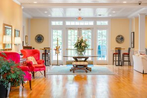 A spacious room with a wooden floor, a central table with chairs, a red armchair, and a white sofa. - Mills Park Hotel (Yellow Springs)