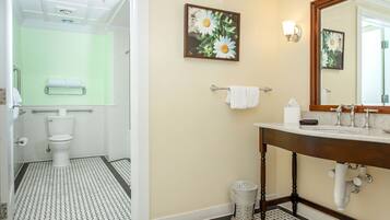 Une salle de bain avec des toilettes, un lavabo et un miroir. Deux serviettes sont suspendues à des porte-serviettes.