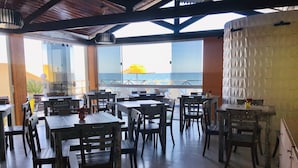 Un restaurant doté d’une terrasse, de tables et de chaises en bois, et offrant une vue sur la mer.