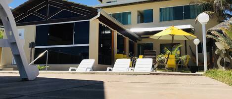 A modern building with a covered outdoor area, including lounge chairs and umbrellas.