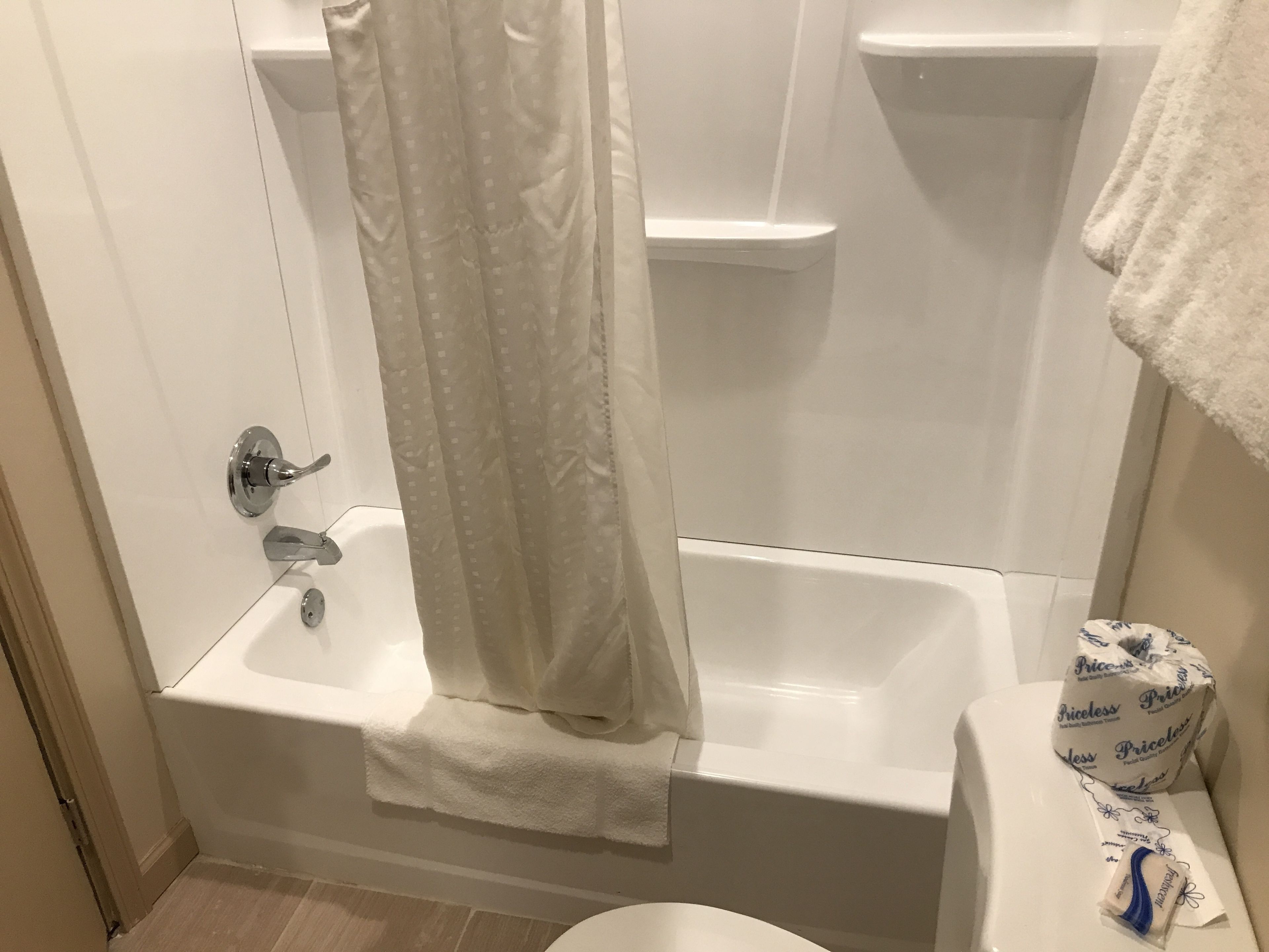Kylpyhuone, jossa on kylpyamme, suihkuverho, wc ja pyyheteline.
