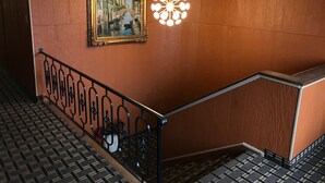 A staircase with a railing, a framed painting of a canal scene, and a modern light fixture.