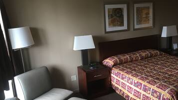 A hotel room with a bed, a chair, a nightstand, and two wall-mounted lamps.