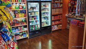 A convenience store with a variety of snacks, beverages, and household items on shelves and in a refrigerated display.