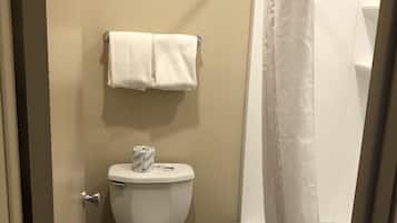Un baño con inodoro, toallero con dos toallas, cortina de ducha y rollo de papel higiénico.