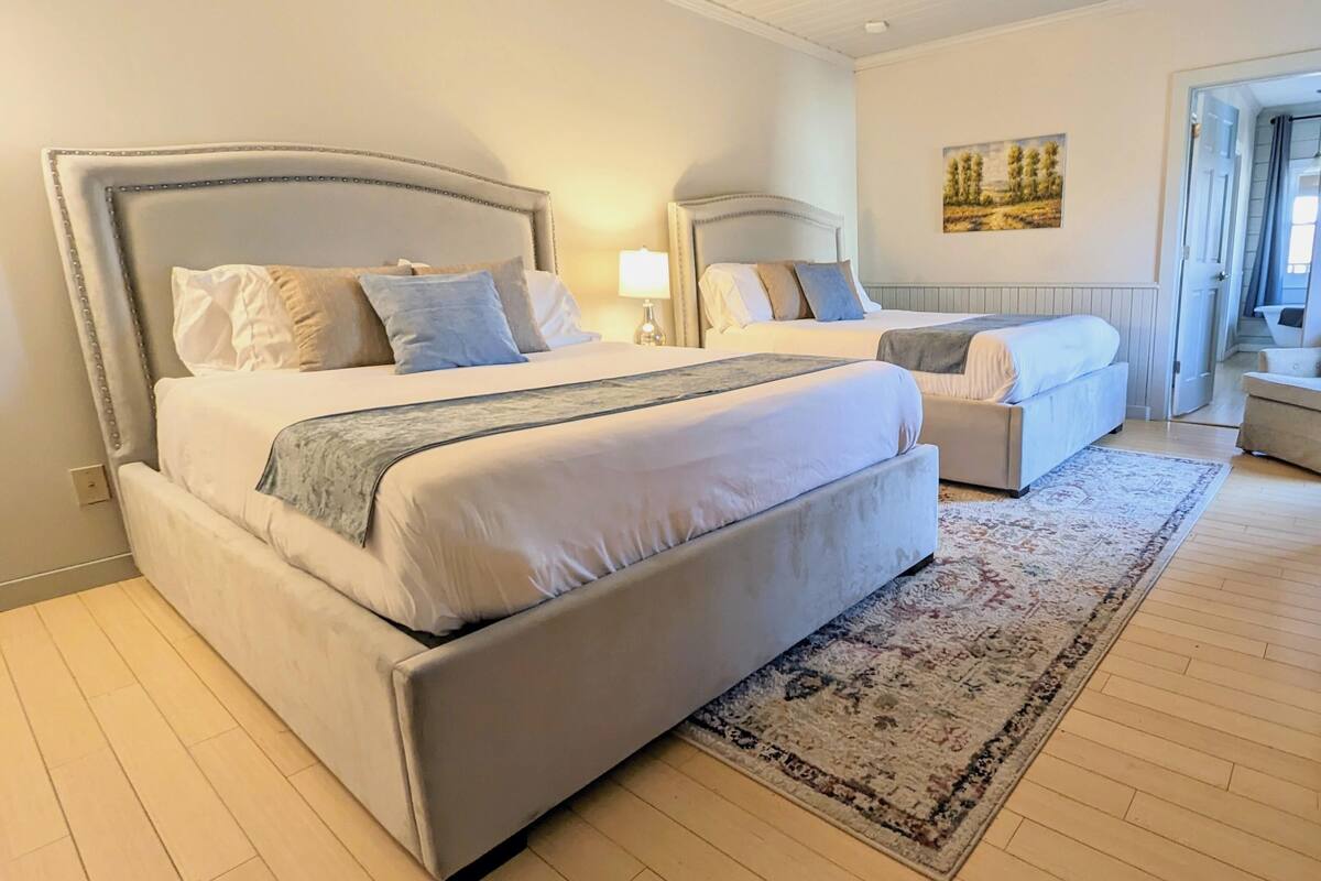 Um quarto com duas camas, um tapete grande e um quadro na parede.