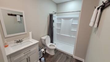Un baño con inodoro, lavabo, espejo y ducha.