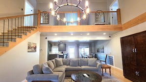 A spacious living area with a large sectional sofa, a coffee table, and a staircase leading to an upper level. - Barefoot Hills (Dahlonega)
