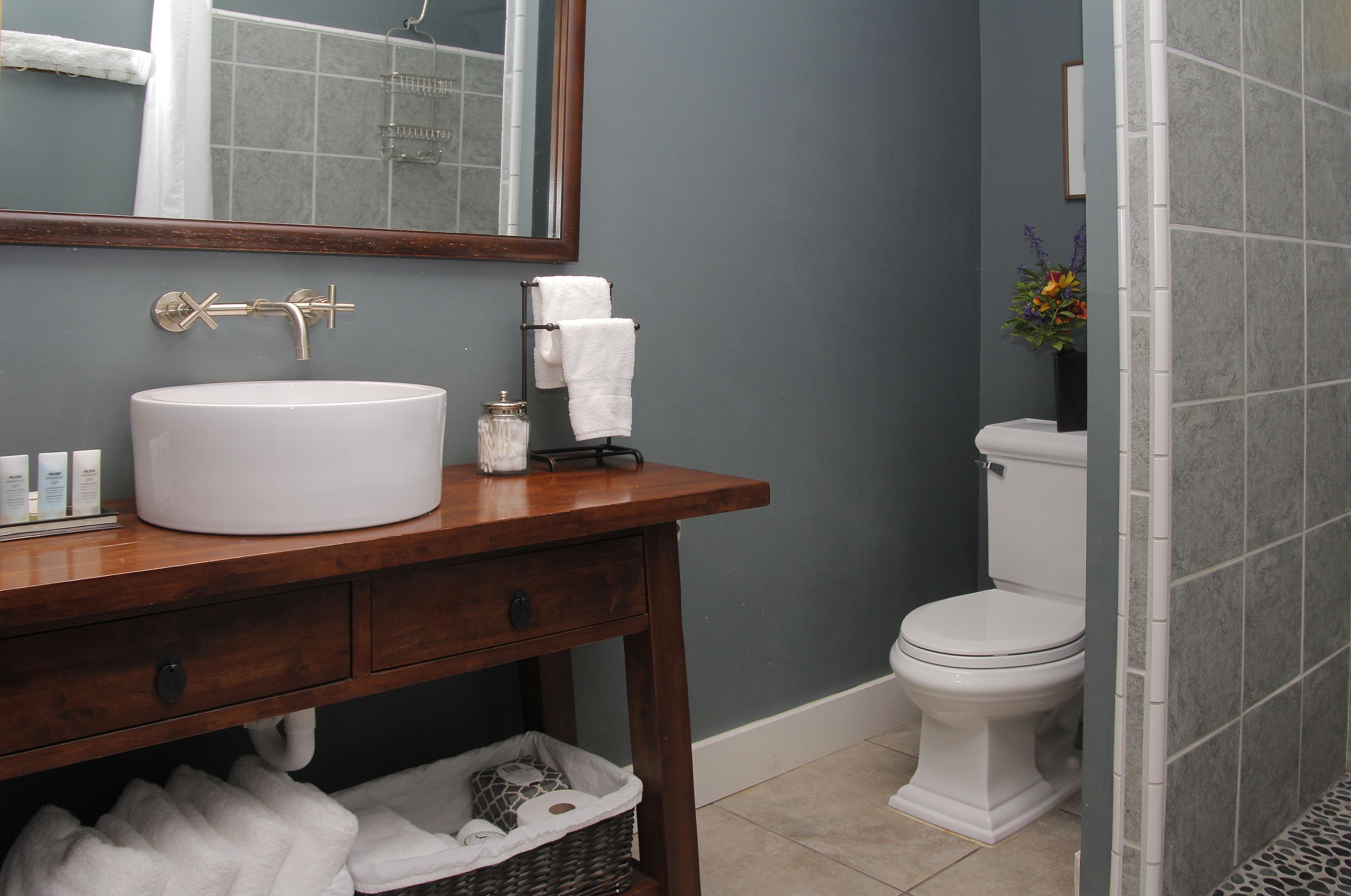 A bathroom with a wooden vanity, white sink, and a toilet.