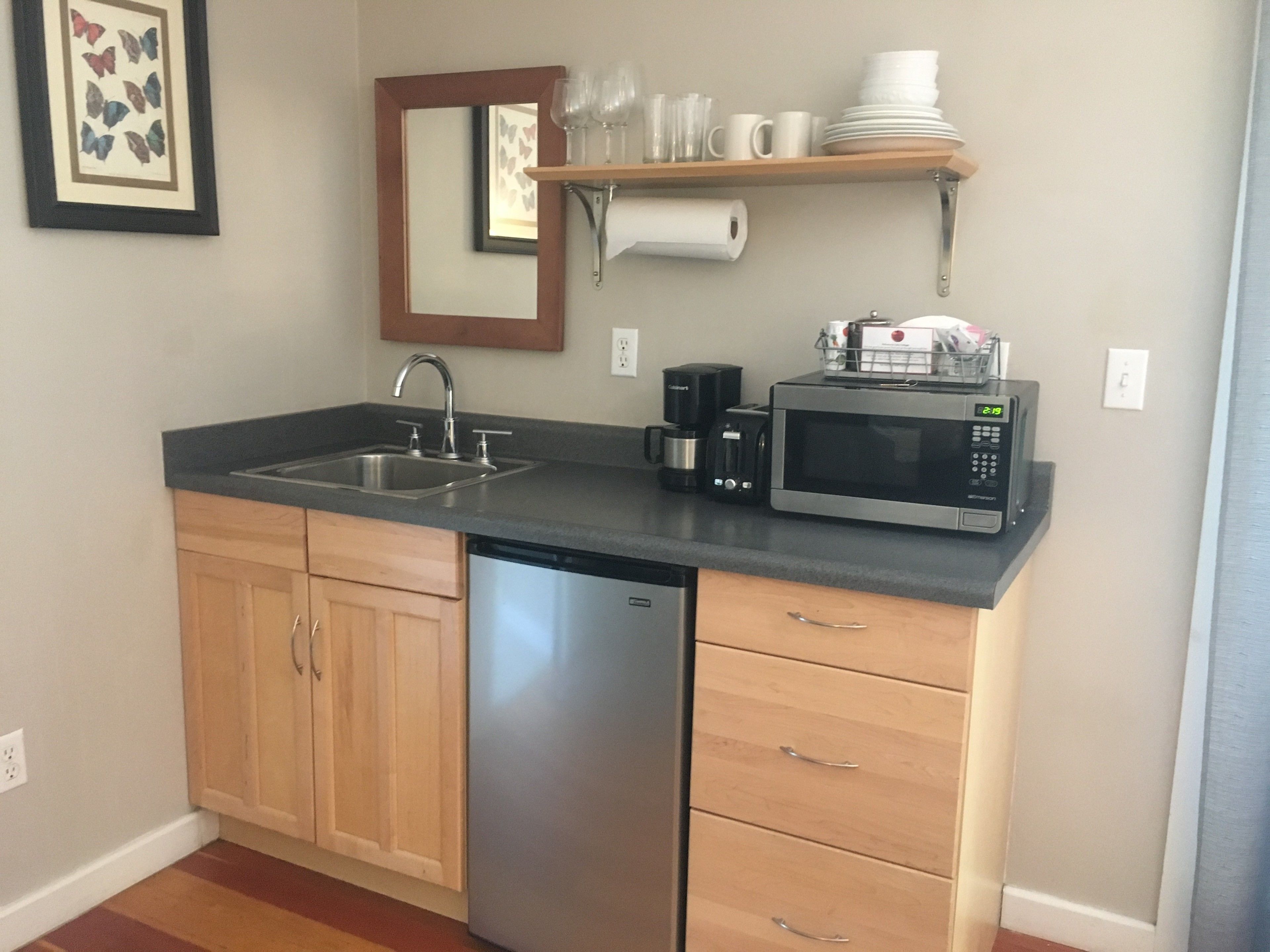 Una cocina compacta con lavavajillas, cafetera, microondas y pileta.