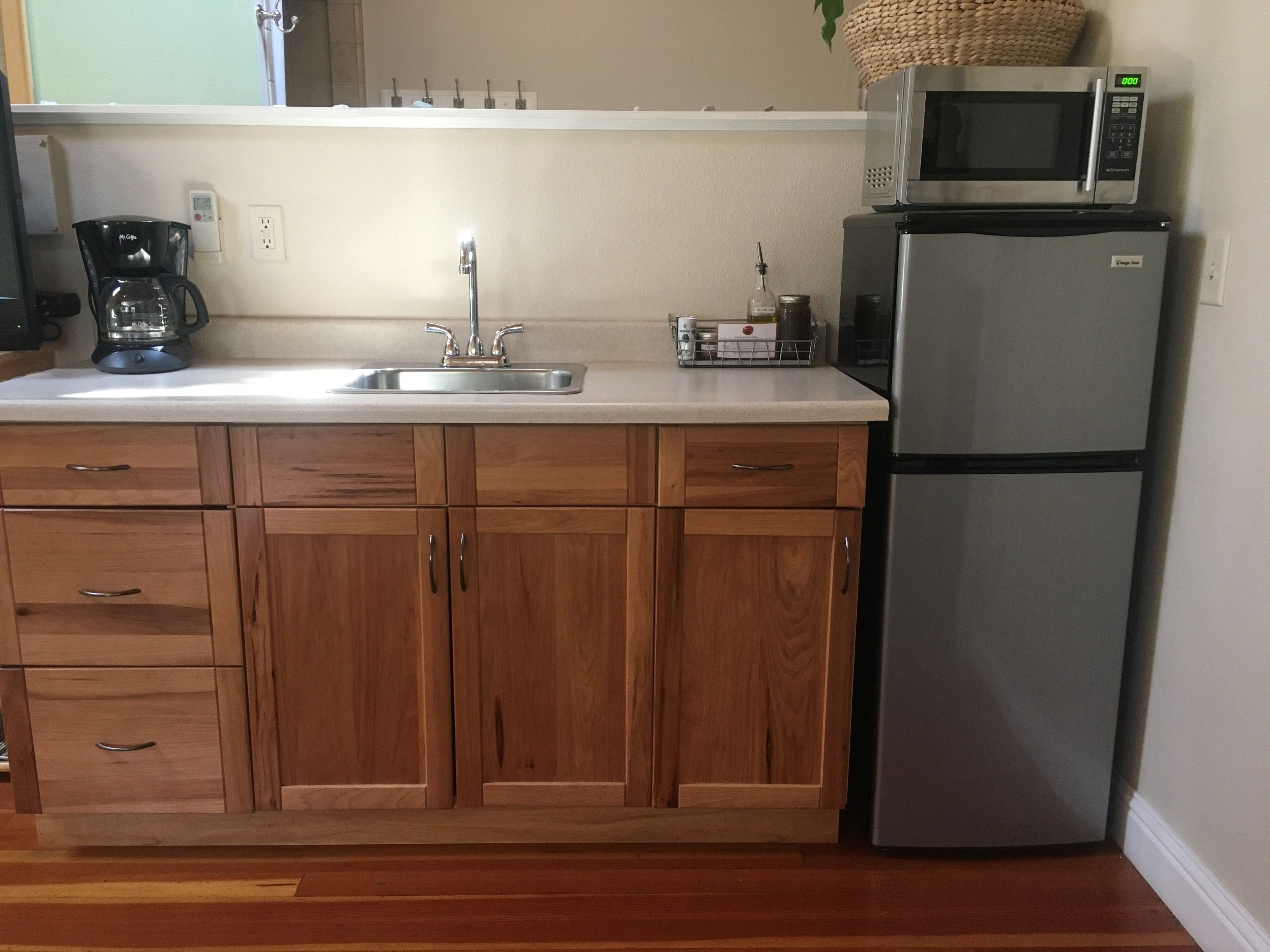 A kitchen with wooden cabinets, a stainless steel refrigerator, a microwave, and a coffee maker.