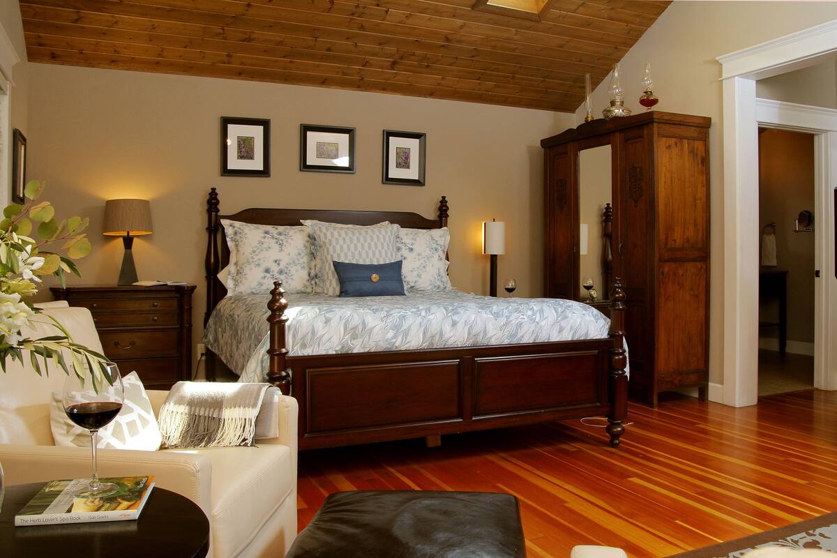 A bedroom with a wooden bed, a nightstand, a lamp, a dresser, and a framed picture on the wall.
