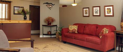 Una sala de estar con un sofá rojo, una mesa de centro de madera y una alfombra estampada.