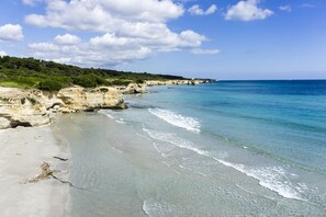 Une plage côtière aux eaux cristallines, bordée d’un rivage sablonneux et de falaises rocheuses.