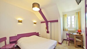 Une chambre à coucher avec un lit, deux chaises, un bureau et une fenêtre avec des rideaux.