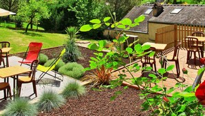 Une terrasse avec des meubles d’extérieur, une table en bois et une rose rouge.