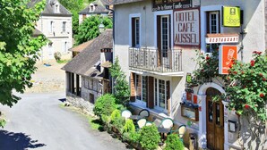 Une rue étroite bordée d’immeubles, dont un hôtel, un café et un restaurant.