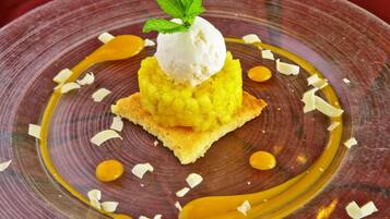 Un dessert composé d’une tranche d’ananas surmontée d’une boule de glace, le tout nappé de sauce au caramel et décoré de feuilles de menthe.