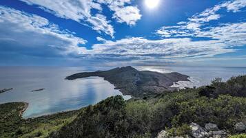 A coastal landscape with a prominent rocky outcrop and a clear view of the sea.