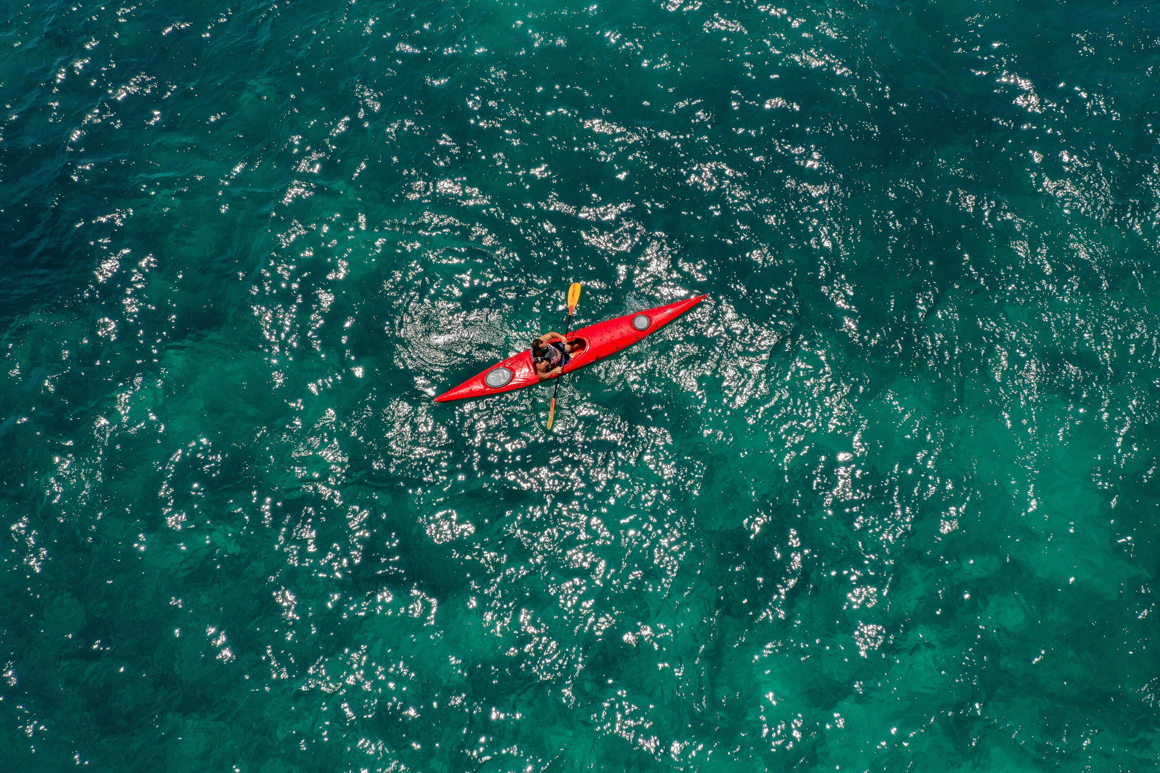 A red kayak on a turquoise sea.