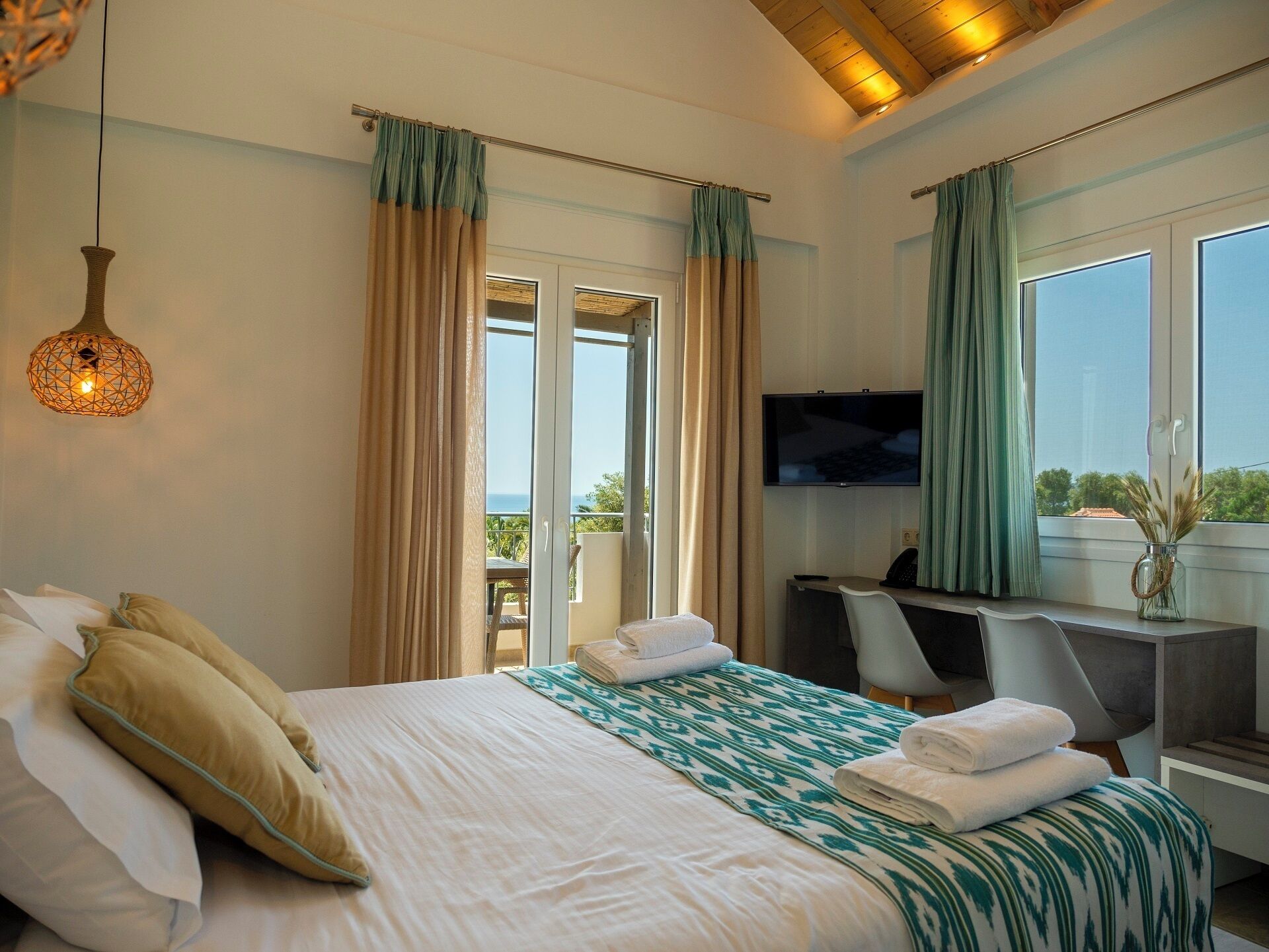A hotel room with a bed, a desk, a television, and a view of the outdoors.