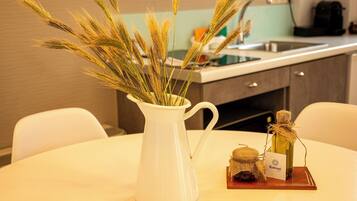 A white ceramic pitcher with wheat stalks on a round table in a modern kitchen with a sink and cabinets.