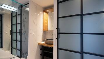 Ein modernes Badezimmer mit Duschkabine aus Glas, Marmorplatten, einem Holzkosmetikschrank und einer Tür mit Frostglas.