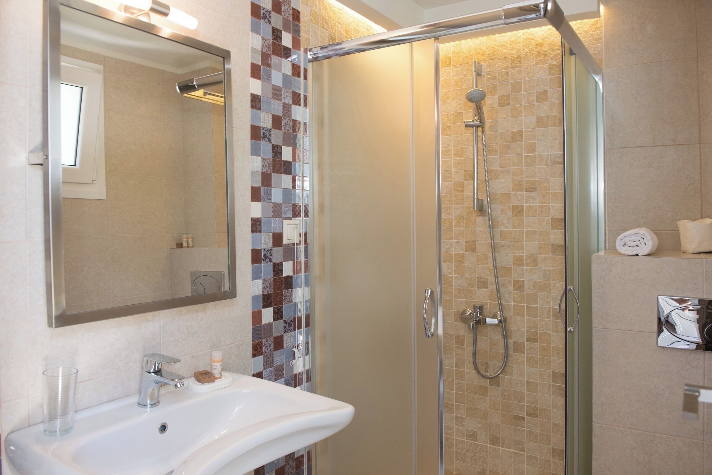 A bathroom with a glass-enclosed shower, a white sink, and a tiled backsplash.