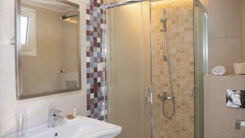 A bathroom with a glass-enclosed shower, a white sink, and a tiled backsplash.