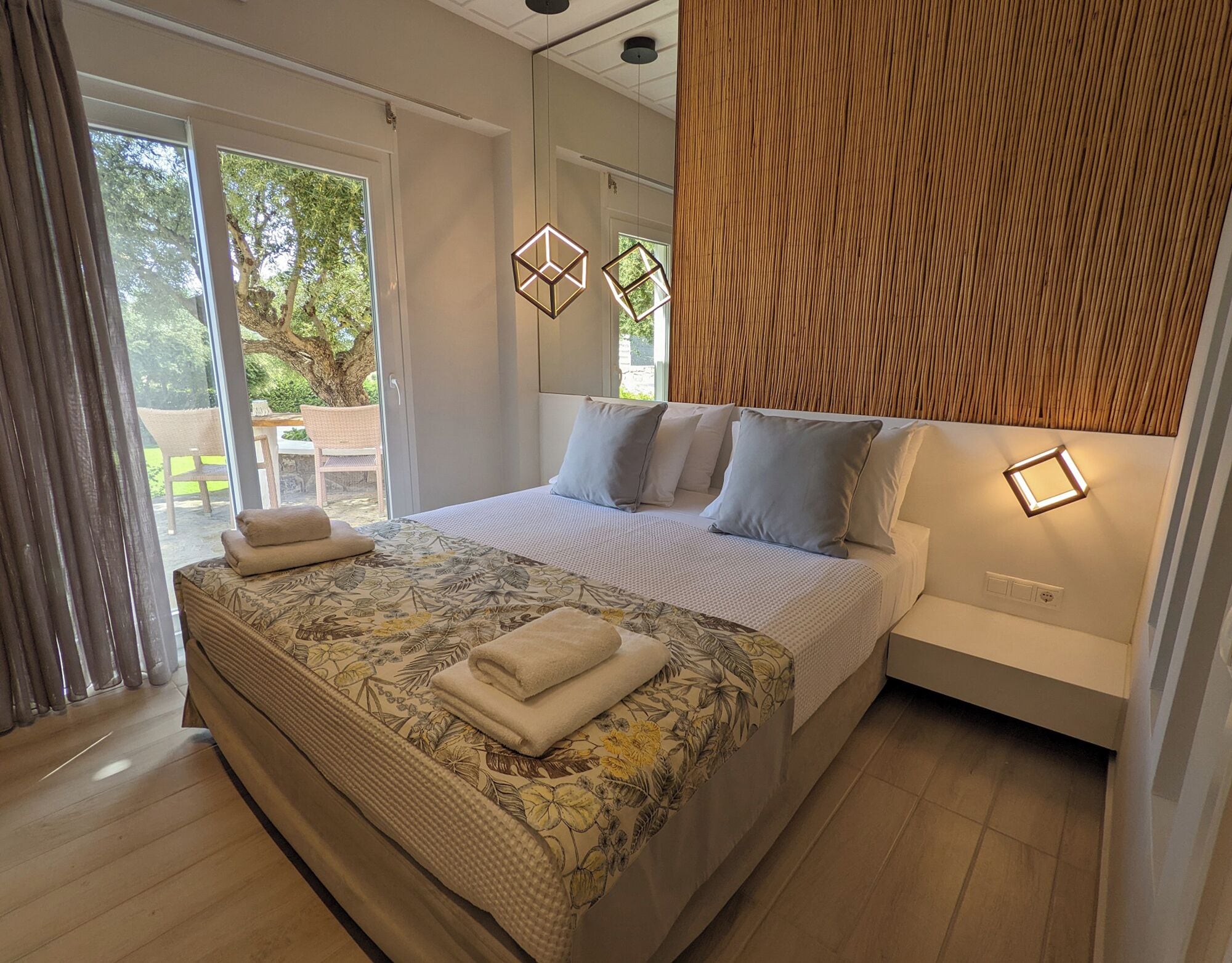 Quarto moderno com cama grande, cabeceira de madeira e vista para o exterior.