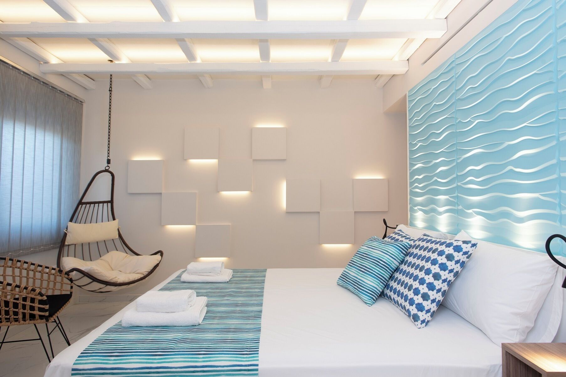 Ein modernes Schlafzimmer mit Bett, Hängesessel und Wand mit integrierter Beleuchtung.