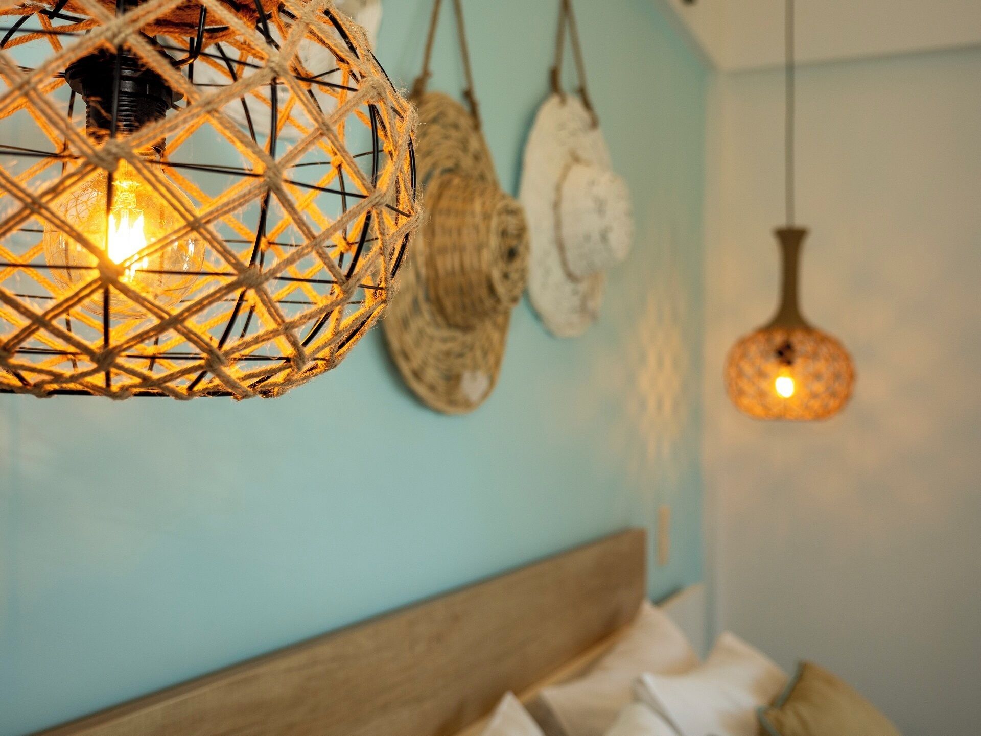 Una stanza con una testiera in legno, un lampadario intrecciato a sospensione e un oggetto decorativo a parete.