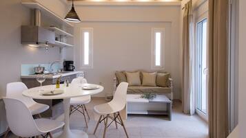 A modern kitchen with white cabinetry, a dining table with chairs, and a sofa in the living area.