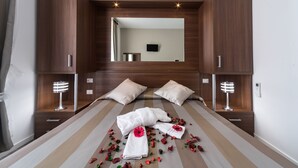 Quarto de hotel moderno com uma cama grande, guarda-roupa de madeira e televisão de tela plana.