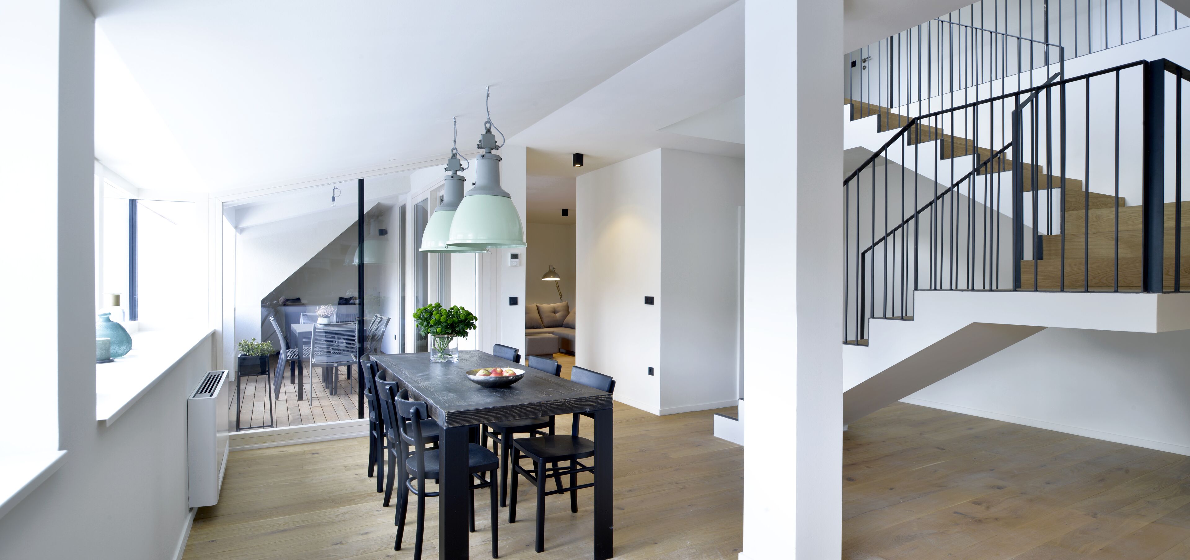 A modern interior with a dining area, staircase, and a view of the outdoors.