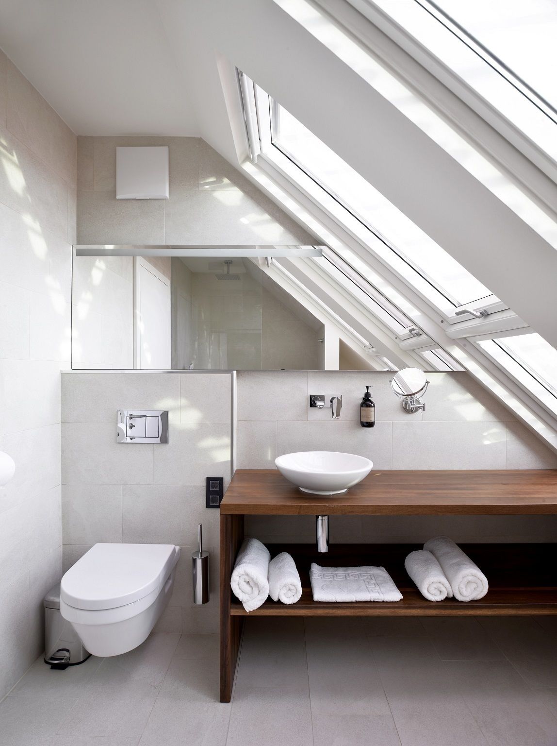 Un baño moderno con tragaluz, un lavabo blanco y un mueble de tocador de madera.