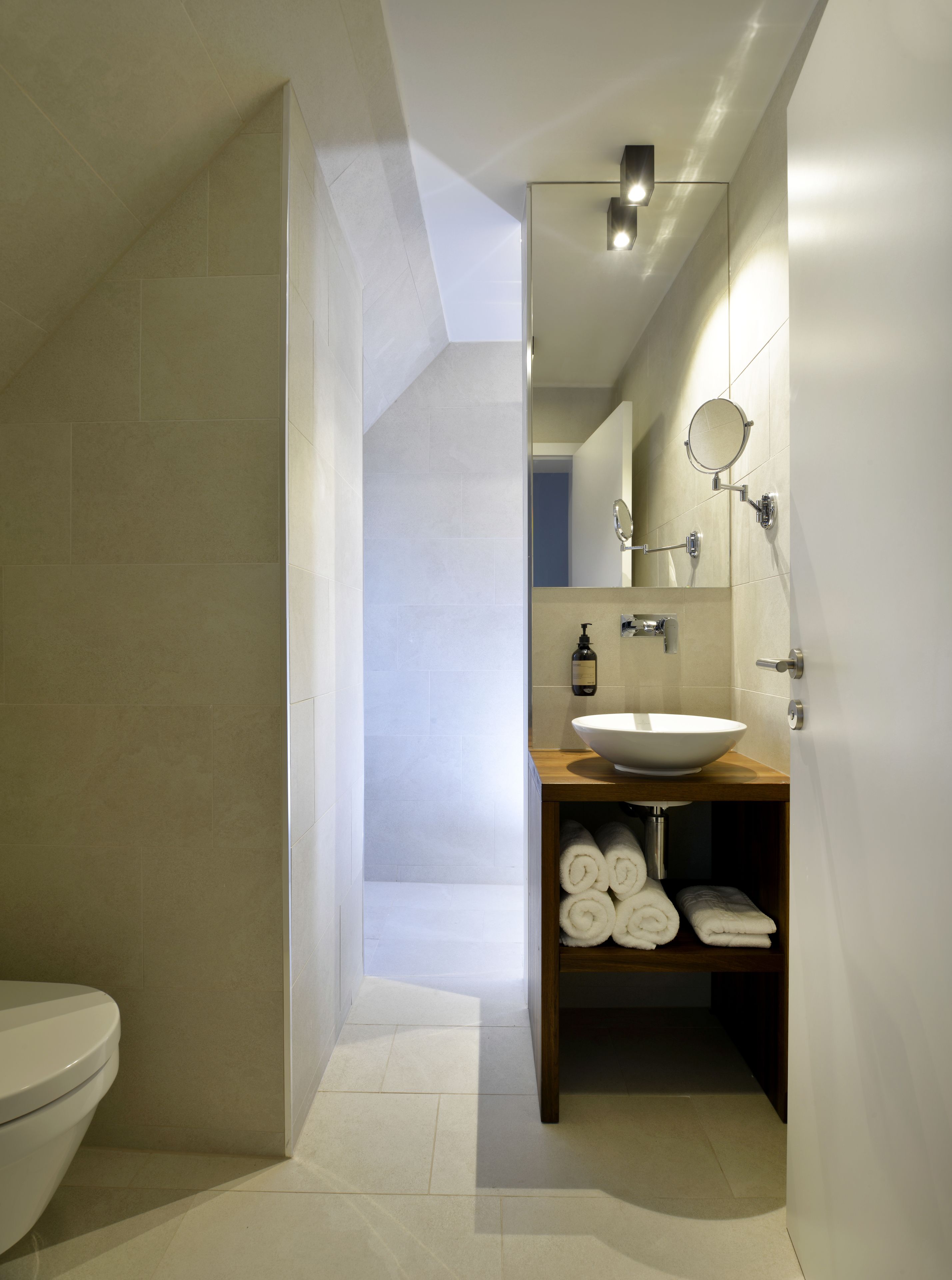 A modern bathroom with a large white sink, a mirror, and a towel rack.